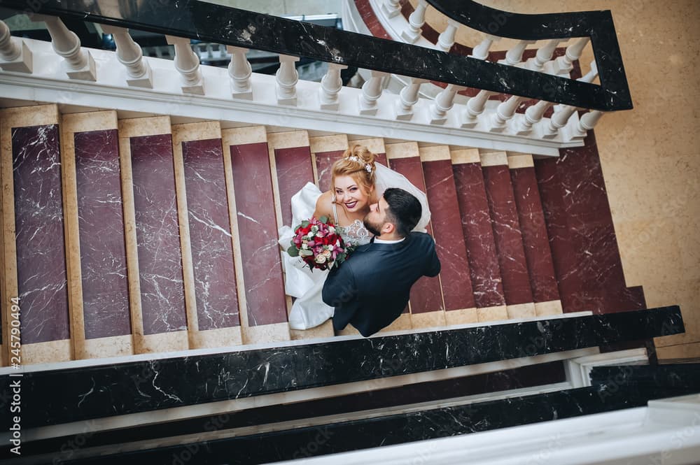 Para mloda sfotografowana z gory na eleganckich schodach.